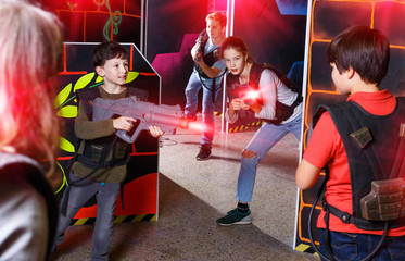 Obraz na płótnie Canvas Group of happy teenagers with laser guns having fun on dark lase