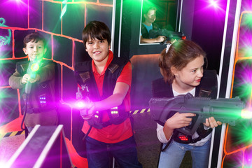 Fototapeta na wymiar Group of happy teenagers with laser guns having fun on dark lase