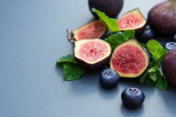 Fresh figs with mint and blueberries. Beautifulf berry, fruit background, frame for design with copy space.