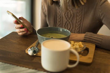 The girl with the phone is having lunch. The blogger is eating the right food. Veggie Green Broccoli Soup