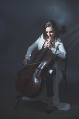 Obraz na płótnie Canvas Beautiful woman in a white coat plays the cello