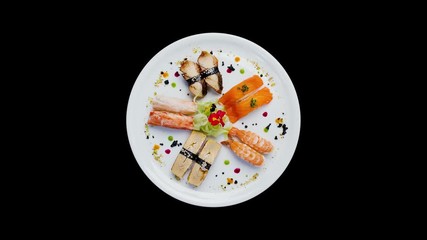Sashimi set rotating on a white round plate, decorated with small flowers, Japanese food. Top view. Isolated on a black background
