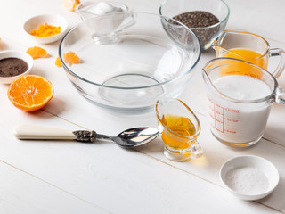 Cooking dessert ingredients with chia, milk and citrus orange on white background. Recipe steps by steps concept.