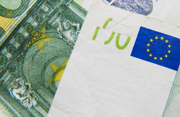 Background of one hundred euros banknote with Europe Union logo. One hundred euros is green. On banknote are visible yellow stars of Europe Union. Banknote on photo is a bit damaged no the edges.