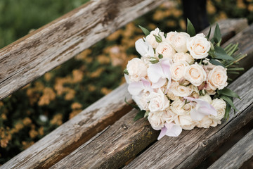 Bridal bouquet with cream roses, on the background of a gray wooden vintage bench.