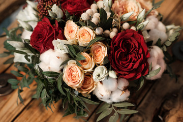 Bridal bouquet with red and orange flowers. Roses and peonies, on the background of a wooden bench.