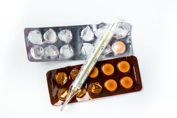 Thermometer and pills lie on a white background