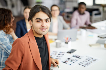Portrait of contemporary Middle-Eastern businessman looking at camera while sitting at table during business meeting, copy space - obrazy, fototapety, plakaty