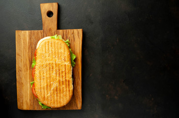sandwich on a cutting board against a background of stone