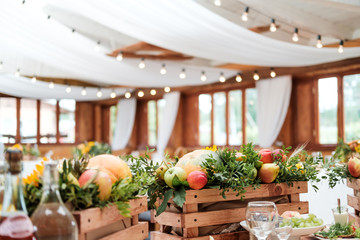 Bright room with white fabrics and vintage garlands of incandescent bulbs on the ceiling. The decor of the served table, the design of the event.