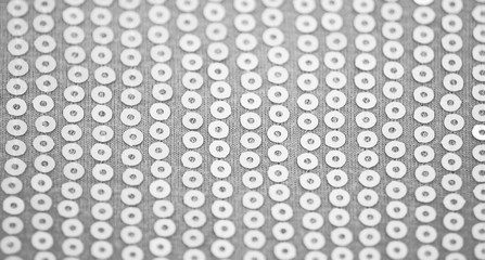 Pale light gray knitted fabric with sequins. Background for wallpaper and other elements of your design with selective Focus.