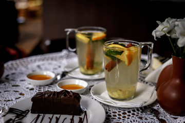 Transparent cup of tea with cinnamon, mint, orange on the table with a beautiful decor and dessert. warming fruit and mint tea in a restaurant