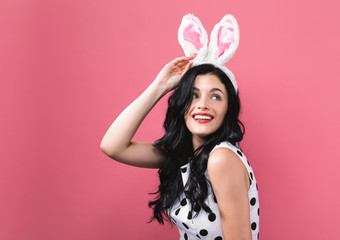 Young woman with Easter rabbit ears on a pink background