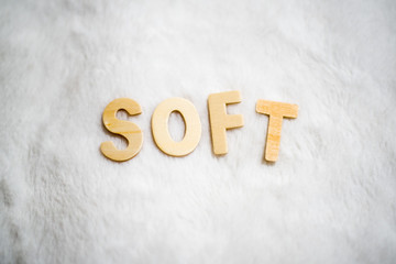 Soft word made with small wooden letters on a white warm fur blanket