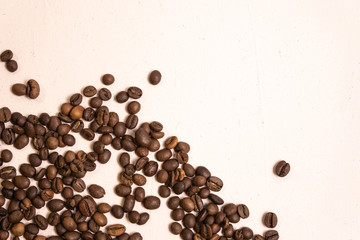 Roasted coffee beans in bulk on a light pink background. dark cofee roasted grain flavor aroma cafe, natural coffe shop background, top view from above, copy space