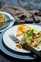 Green spinach pasta with vegetables mushrooms wheat tost and quail eggs on concrete texture background