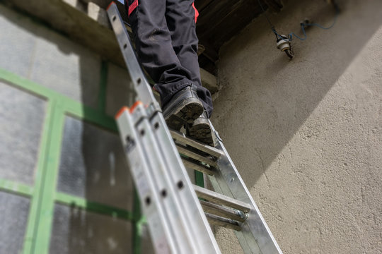 Texture, Background, Spring Repairs, Man Uploaded On A Folding Ladder To Repair The Roof Of An Old Rural House. Concept Village.