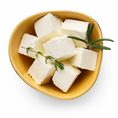 Feta cheese cubes in bowl on white
