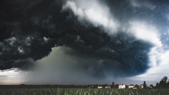 Muddy wet countryside corn field and dark storm clouds. Blue tint