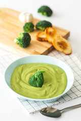 Broccoli cream soup in pastel blue plate on white background. Healthy food concept