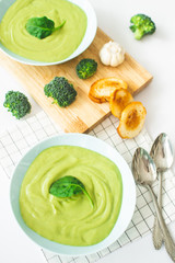 Broccoli cream soup in pastel blue plate on white background. Healthy food concept