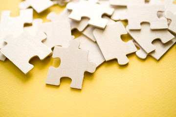 Wooden puzzles on a yellow background, close-up, soft focus