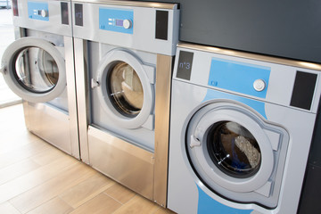 row of industrial washing machines in a public Laundromat Dryers laundry