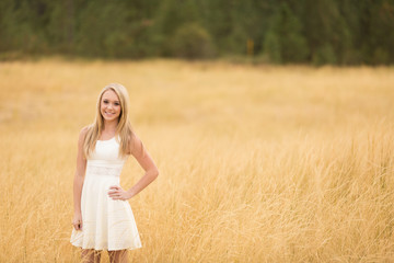 Fototapeta na wymiar Beautiful teen posing in golden field in sundress