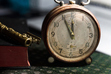 Vintage background. Old alarm clock, book and metal key on a desk.