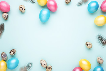 Fototapeta na wymiar Frame made of colorful Easter eggs on turquoise background. Top view, copy spase, minimal styled.
