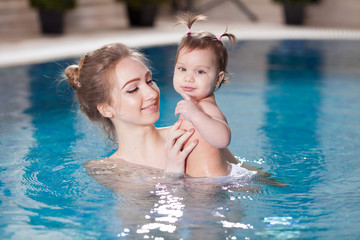 young mother bathes the baby in the pool.