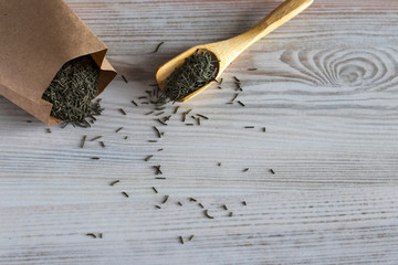 Wooden spoon with green tea and craft tea bag on a white background