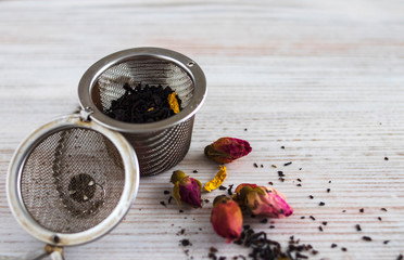 Liner Black and Herbal Tea with Rose Flowers with Metallic Infuser Ball on a white backgraund