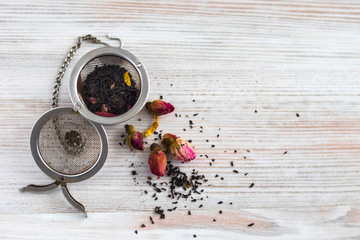 Liner Black and Herbal Tea with Rose Flowers with Metallic Infuser Ball on a white backgraund