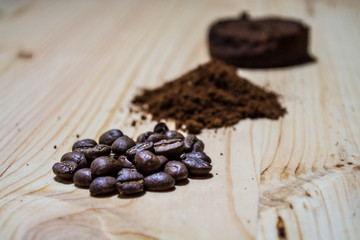 Three stages for preparation of coffee: grain, crushing and the pressed tablet. Wooden surface. Espresso. Work barista.