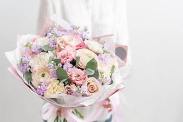 beautiful fresh cut bouquet of mixed flowers in woman hand. the work of the florist at a flower shop. Delicate Pastel tones color