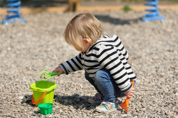 Cute toddler baby girl playing with shovel at playground