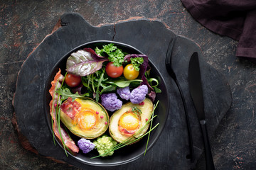Baked avocado with egg and bacon ,flat lay on dark background