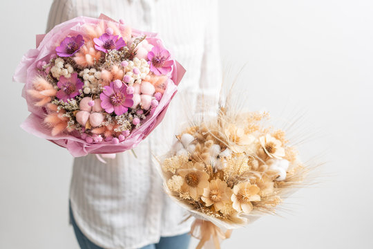 Two beautiful bouquets of mixed dried flowers in woman hand. the work of the florist at a flower shop. Delicate Pastel tones color
