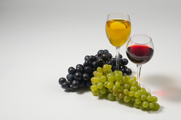 Bunches of grapes and glasses of wine on a white background