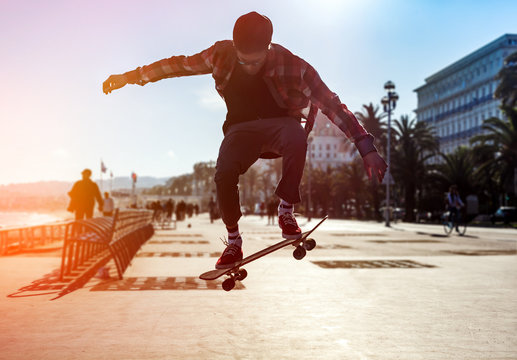 Silhouette of skateboarder jumping in the city of Nice on background of promenade near the sea
