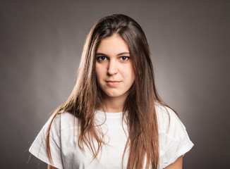 portrait of serious young girl on a gray background