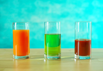 Fresh orange, apple and tomato juices in glasses in bright table setting.