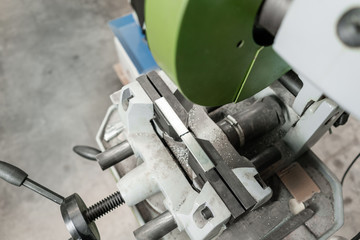 vise to secure the workpiece. Circular saw machine. Cutting a metal and steel with with sharp, circular blade in workshop interior. Tool store or exposition stand.
