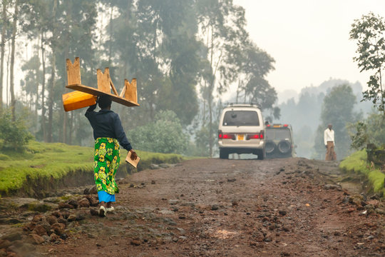 Rwandan woman in colorful traditional cloth walikung and carrying bench on her head, Kigali, Rwanda