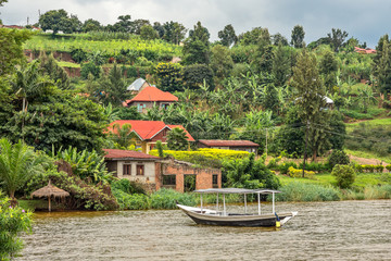 Roof boat anchored at the coast with rwandan village in the background, Kivu lake, Rwanda