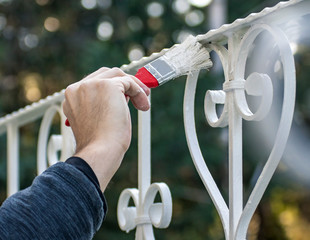 Man painting with brush outdoor fence in white, close up