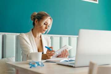 Beautiful girl working out a plan of the project and concept. Girl paints a website design on a laptop. student prints a message on the phone in the messenger. Development. Digital marketing