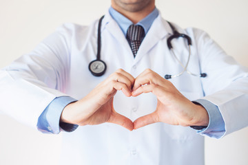 Close up of doctor's hands making heart shape isolated on white background