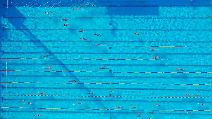 Aerial drone top view photo of open outdoor deep turquoise pool with swimmers practising